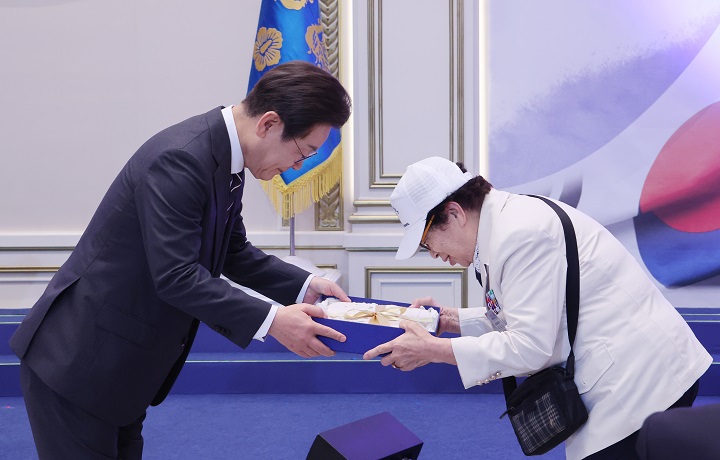 이재명 대통령이 27일 청와대 영빈관에서 열린 '호국 보훈의 달, 대통령의 초대' 행사에서 특별 초청대상자인 이춘자 씨에게 광목이불을 선물하고 있다. 2025.6.27(저작권자(c) 연합뉴스, 무단 전재-재배포 금지)