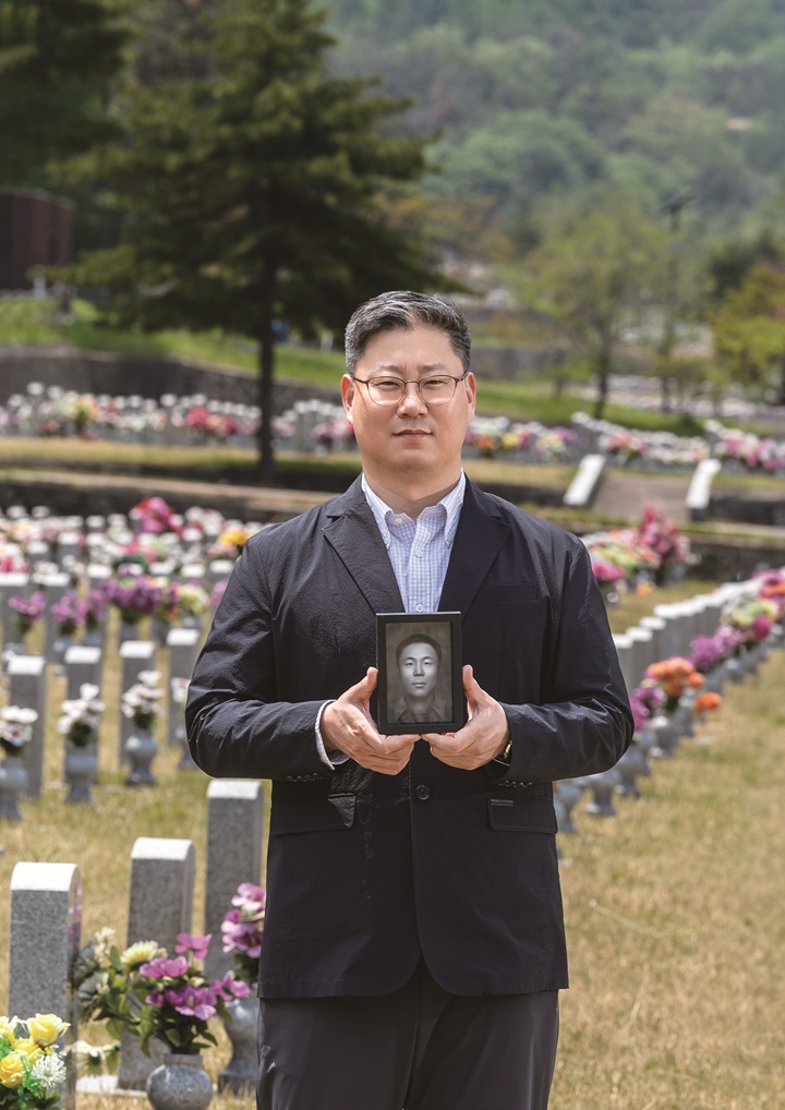 국방부 유해발굴감식단 이규상 중앙감식소장이 6·25 전사자 얼굴 복원 프로젝트 1호 송영환 일병의 영정을 들고 있다. 사진 C영상미디어