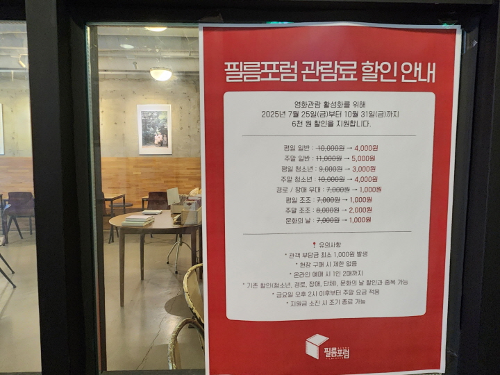 극장 출입문 벽면에 '영화관람 활성화를 위해 6천 원 할인을 지원합니다'라는 안내문이 붙어 있다.