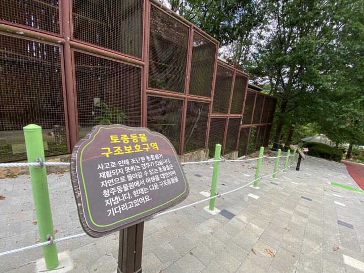 새가 있는 우리가 나열되어 있고, 그 앞에 '토종동물 구조보호구역'이라 적힌 팻말이 꽂혀있다.