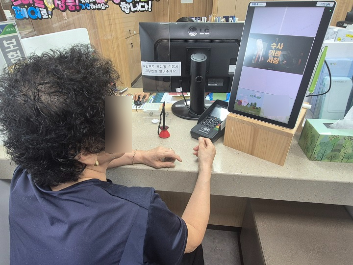 은행에서 보이스 피싱 예방 동영상을 시청 중인 어머니.