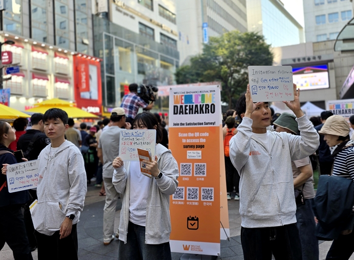 안내자들이 티켓을 제공하는 이벤트 안내판을 들고 서 있다.