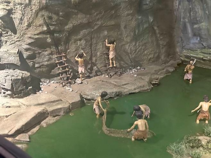 사다리를 타고 암각화를 새기는 선사인들의 모습을 재현한 모형.