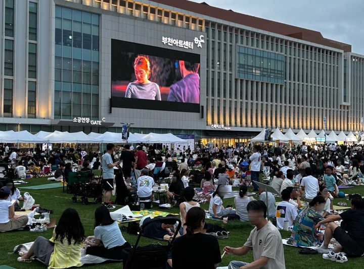 잔디밭에서 야외 상영을 즐기는 시민들의 모습.