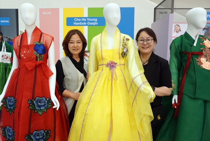 황영아 협회장과 조하영 디자이너가 한복 옆에서 사진을 찍고 있다.