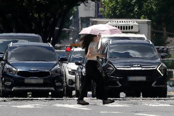 폭염이 연일 계속되는 25일 오후 대구 중구 달구벌대로에서 양산을 쓴 시민이 아지랑이가 피어오르는 도로를 건너고 있다.(ⓒ뉴스1, 무단 전재-재배포 금지)