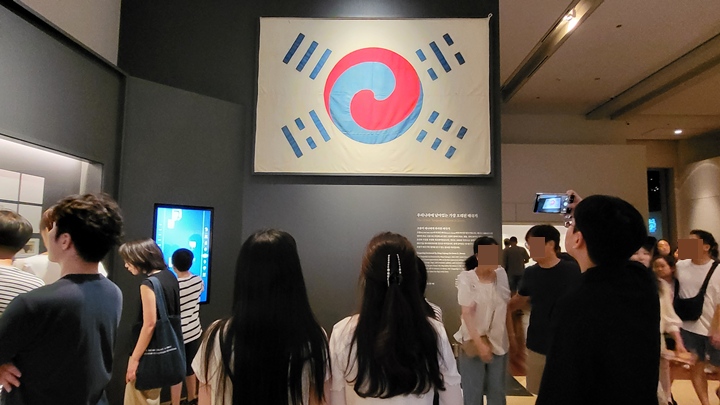 데니 태극기를 보고 있는 관람객들.