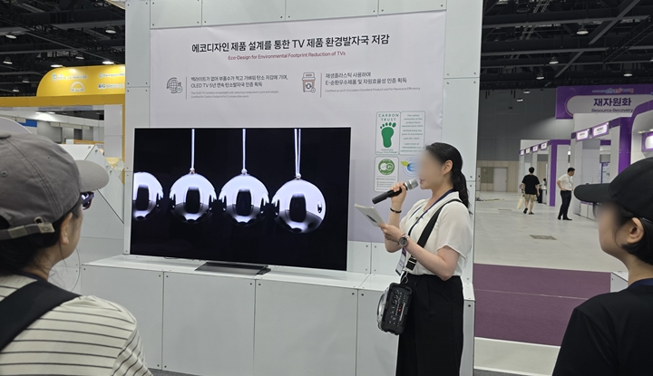 안내자가 재활용 플라스틱을 사용하여 생산된 TV에 관해 설명을 해주고 있다.