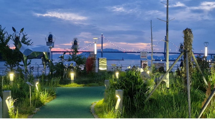 다도해에 둘러싸인 고흥의 청명한 초저녁, 석양빛과 불빛이 어우러진 평온한 바다 풍경.