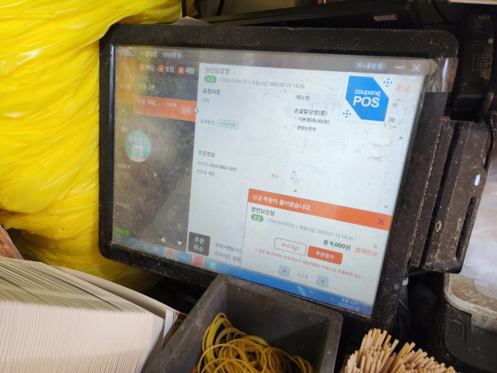 고객이 스마트폰 앱으로 치킨을 주문하자, 상점의 단말기에 주문을 알리는 알림이 뜨고 있다.
