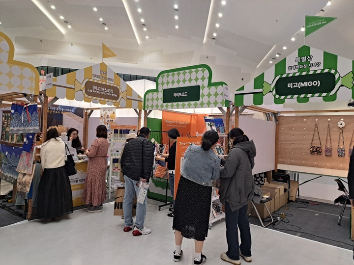 관람객들이 부스 앞에서 기념품을 구경하고 있다.