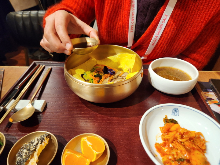 이탈리아 국적의 안드레아가 보자기 비빔밥을 만든 후 먹기 직전에 간장을 넣고 있다.