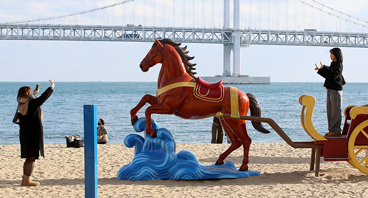 부산 수영구 광안리해수욕장을 찾은 관광객들이 2026년 병오년(丙午年) 붉은 말의 해를 맞아 설치된 새해 말 조형물에서 기념사진을 찍고 있다. 2025.12.22 (ⓒ뉴스1, 무단 전재-재배포 금지)