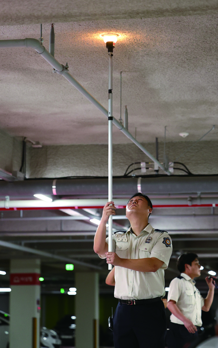 한 아파트 지하주차장에서 소방관이 화재감지기를 점검하고 있다.