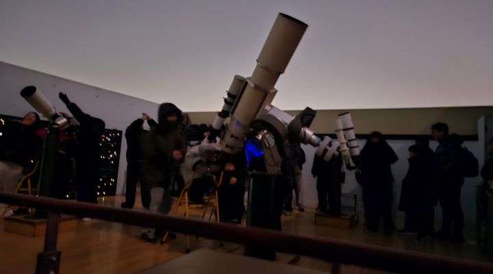 야외 관측 공간에 설치된 망원경을 이용해 밤하늘을 관측하는 참가자들. 아이들이 직접 망원경을 조작하며 별을 찾고 있다.