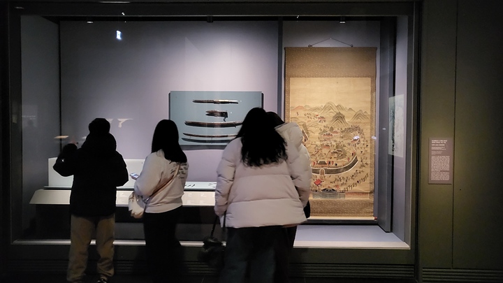 임진왜란의 두 번째 전투인 동래성 전투를 그린 그림인 <동래부 순절도>를 감상하고 있는 관람객들.