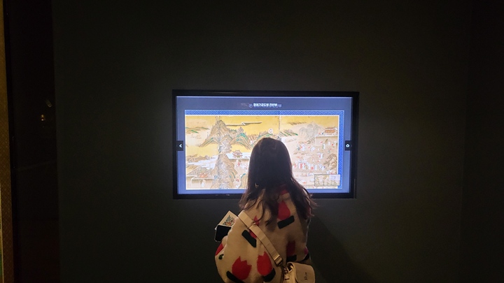 영상 매체로 설명을 감상하고 있는 관람객.