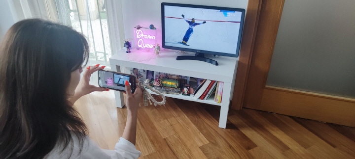 사라가 김상겸 선수가 은메달을 딴 뒤 환호하는 순간을 TV로 시청하면서 사진으로 촬영하고 있다.(사진 제공=사라)