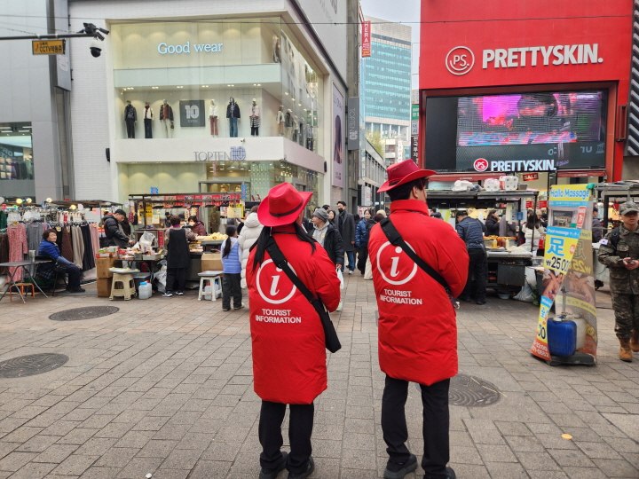 인파로 가득한 명동 한복판에 빨간 옷을 입은 '움직이는관광안내소'가 외국인 관광객의 요청에 응대하고 있다.