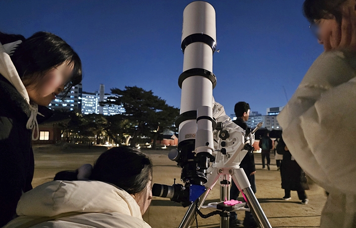 행사에 참여한 사람들이 망원경으로 하늘을 보고 있다.