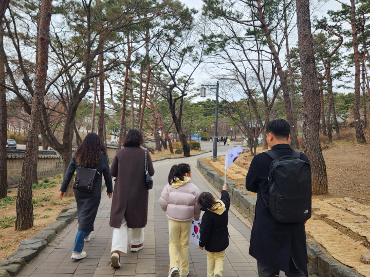 효창공원 산책로를 따라 걷는 길에 태극기를 손에 든 아이와 부모가 함께 걷고 있었다.