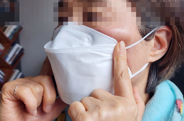 마스크 양옆을 손으로 감싸 밀착도를 확인하는 측면 모습