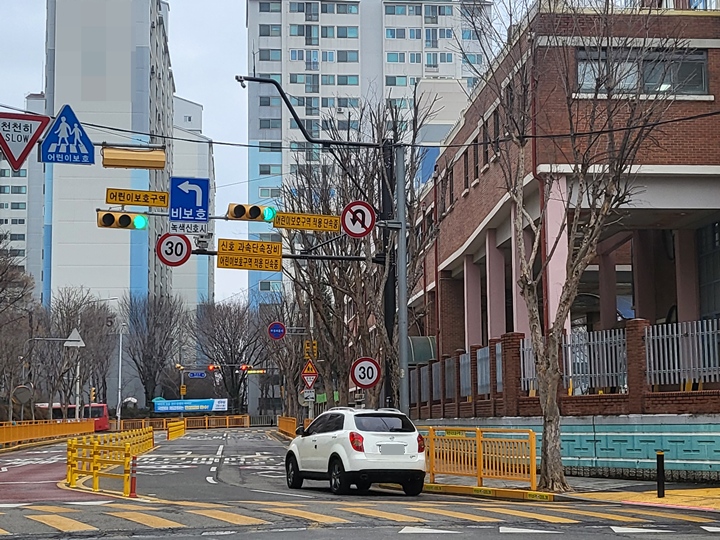 어린이보호구역 내에서 차량이 서행하고 있다.