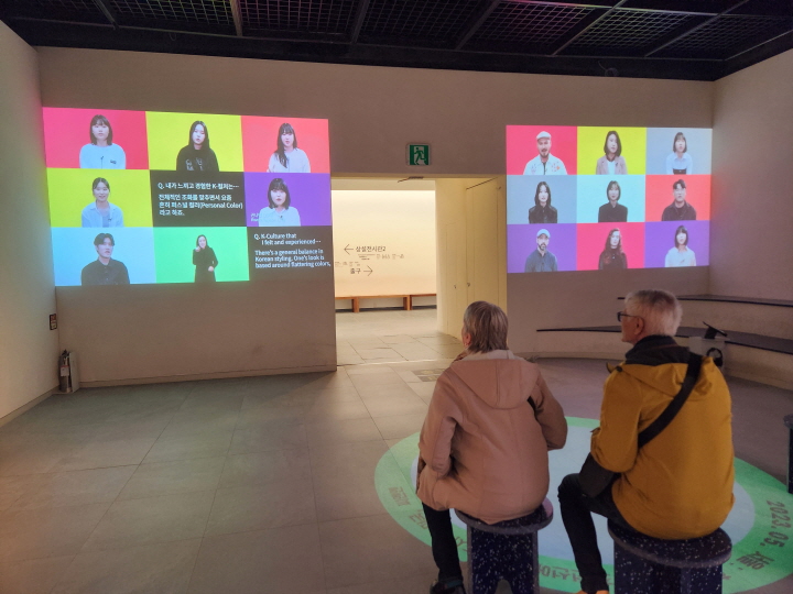 'K-문화'에 대해 다양한 국적의 사람들이 말하는 것을 외국인 관광객이 시청하고 있었다.