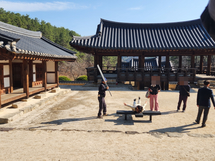도엄서원을 방문한 일행이 앞마당에 설치해둔 곤장을 체험하고 있다.