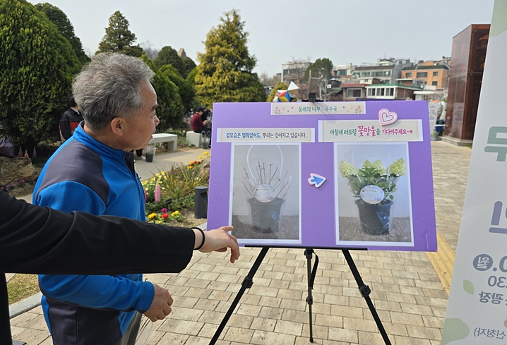 어르신이 목수국 안내를 유심히 보고 있다. <본인촬영>