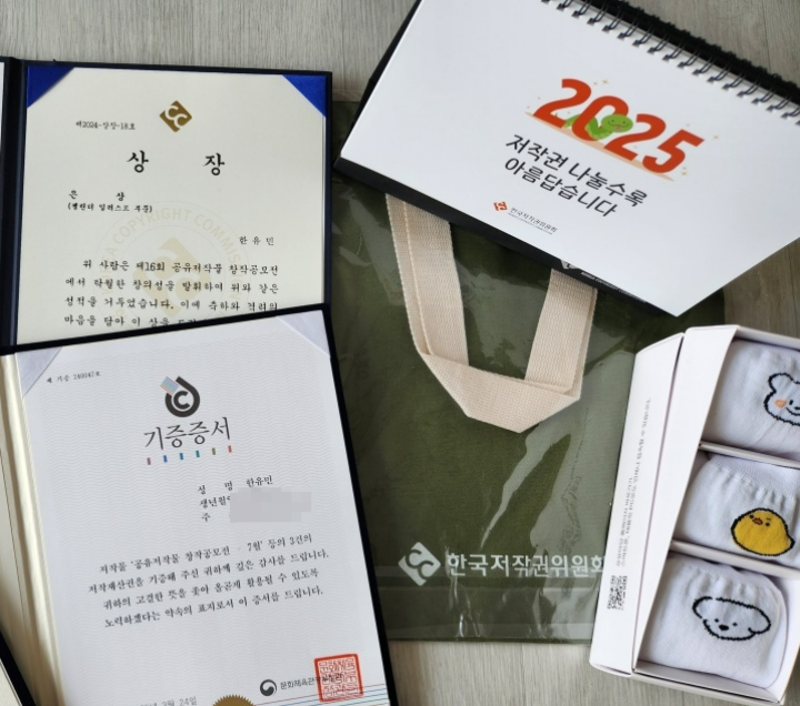 저작권을 기증한 후 받은 상장, 내 일러스트가 포함된 공유저작물 달력, 각종 굿즈의 모습 (본인 촬영)