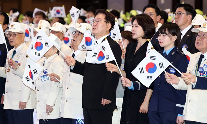 이재명 대통령과 김혜경 여사가 25일 경기 수원시 영통구 수원컨벤션센터에서 열린 6·25 전쟁 제76주년 기념식에서 태극기를 흔들며 6·25 기념 노래를 제창하고 있다. (청와대통신사진기자단) 2026.6.25(ⓒ뉴스1, 무단 전재-재배포 금지)