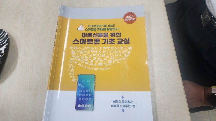 책상 위에 놓인 '어르신들을 위한 스마트폰 기초 교실' 교재 표지