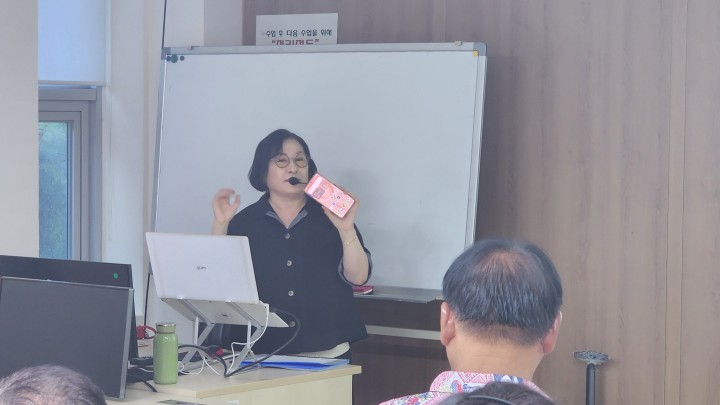 강사가 스마트폰을 들고 수강생들에게 조작법을 설명하는 모습