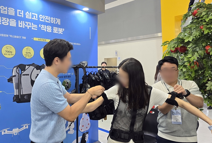 관람객이 어깨 부담을 줄여주는 무동력 착용형 로봇 '엑스블 숄더'를 체험하고 있다. <본인 촬영>