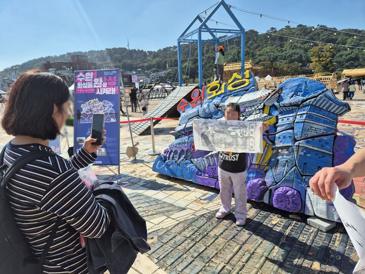 수원화성 탁본 뜨기 체험 후 완성 작품을 들고 기념사진을 찍는 가족 (본인 촬영)