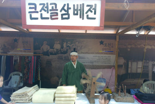 포전의 삼베가게 상인이 지나가는 사람들에게 상행위를 하고 있다.